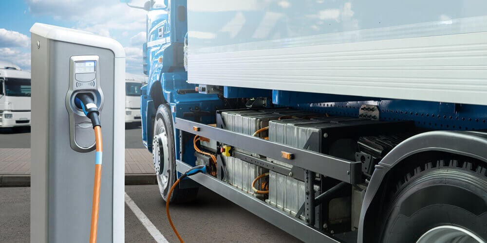 Fleet operator using an electric vehicle (EV) charging station to charge white and blue truck. 
